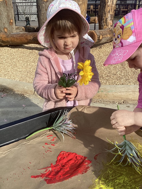 Two children painting with flowers
