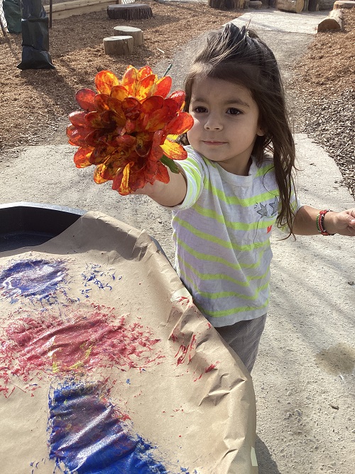 A child holding up a paint covered flower