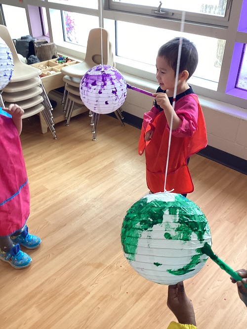 A child painting a suspended lantern.