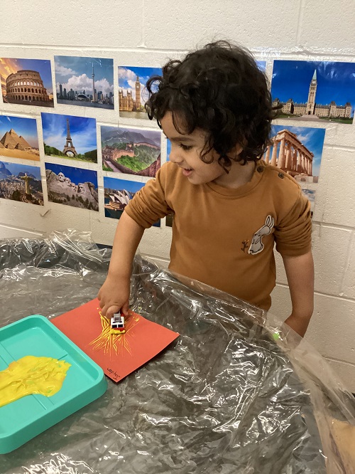 A child using a firetruck to paint with.