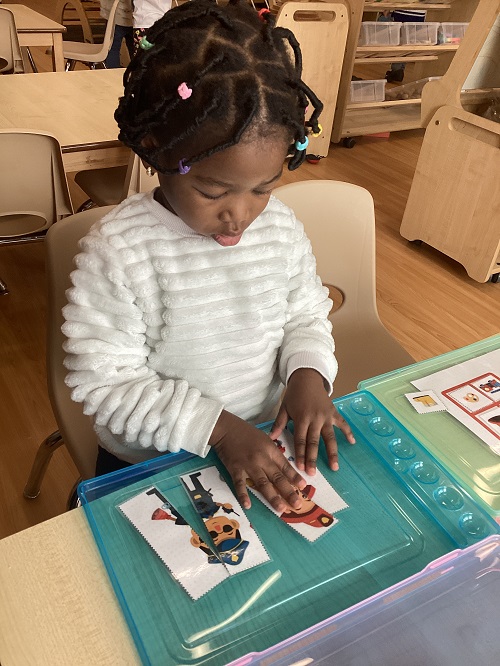 A child sitting at a table working on a puzzle.