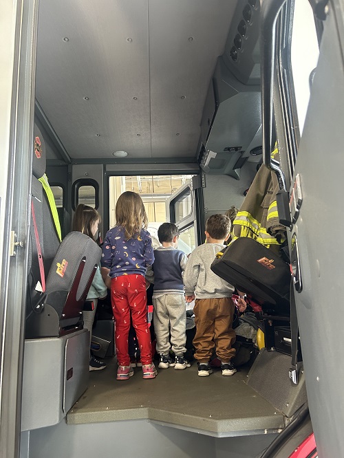 A group of children standing in a fire truck.