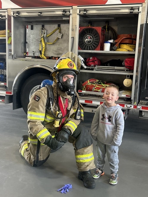 A child standing and smiling with a firefighter.