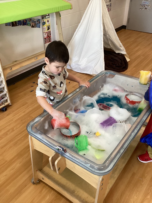 A child exploring in the filled sensory bin.
