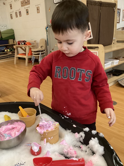 A child exploring with foam in the tuff tray.