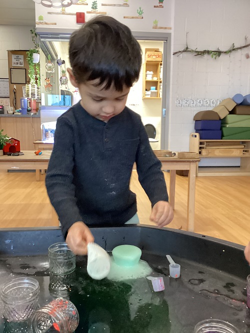 A child exploring items in the tuff tray.