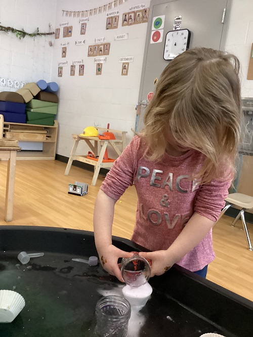 A child exploring with items in the tuff tray.
