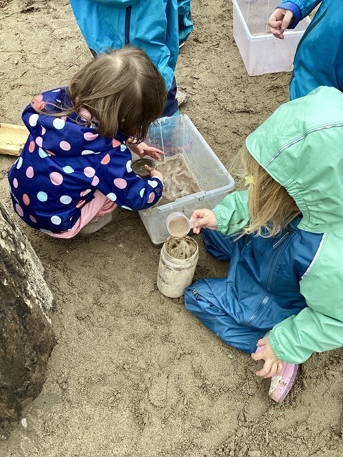 Children using different tools to transport water from a bin.