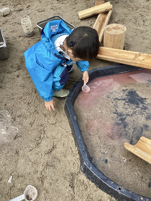 A child scooping water in a tuff-tray.