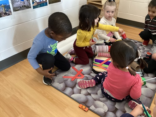 Children sitting on the carpet working with building materials.