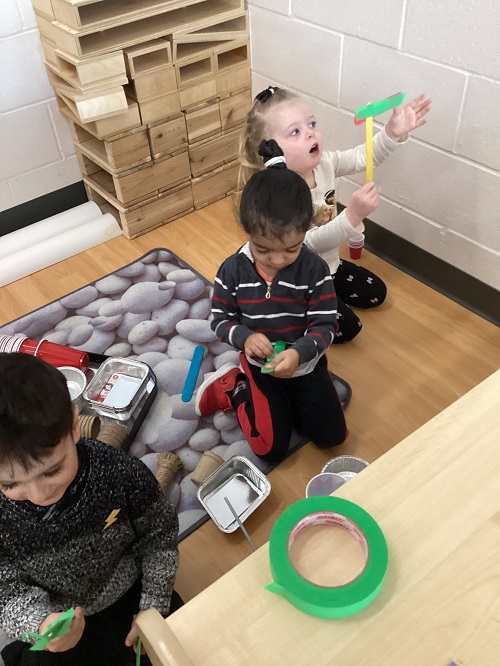Children sitting on the carpet working with building materials.
