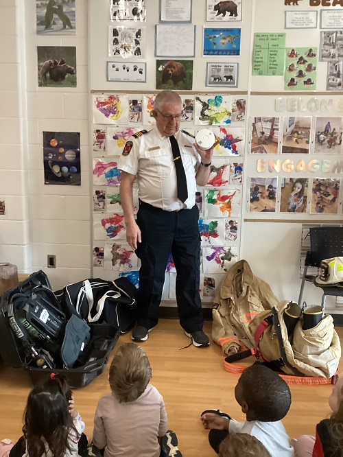 A firefighter showing a smoke detector to a group of children