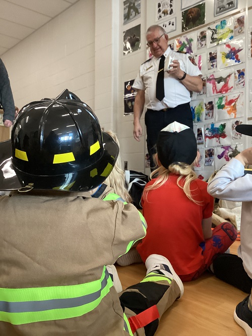 A firefighter showing a smoke detector to a group of children
