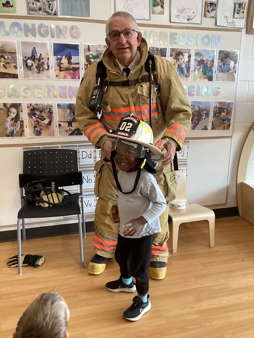 A firefighter holding their helmet over a child's head