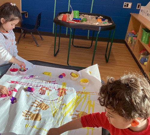 Two children painting with cars.