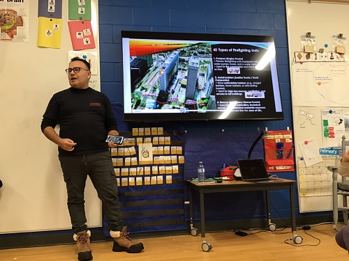 An individual standing beside a screen, giving a presentation