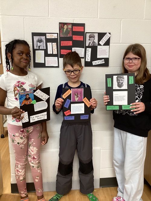 A small group of children holding up the posters they made