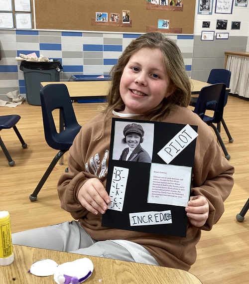 A child holding up a poster they made