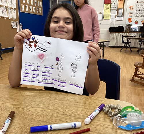 A child holding up a valentine's card they made