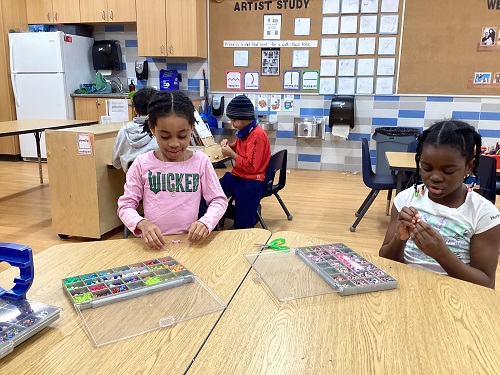 Two children at a table doing beadwork