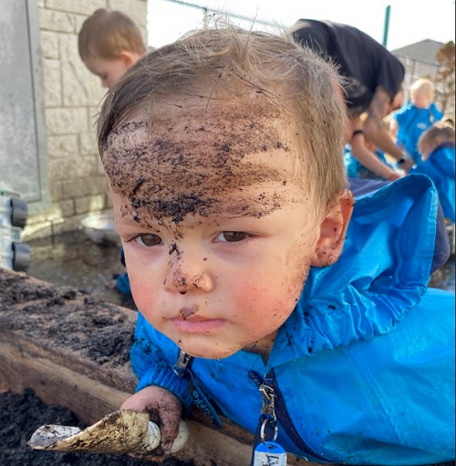 A child has mud on their face.