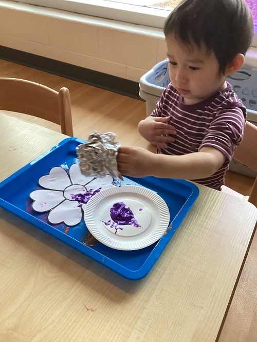 A child stamp-painting their flower.