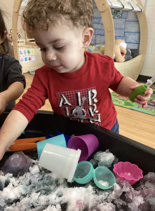 A child exploring with a dropper and coloured snow.