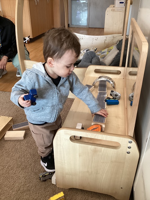 A child creating a track for their cars while using blocks.
