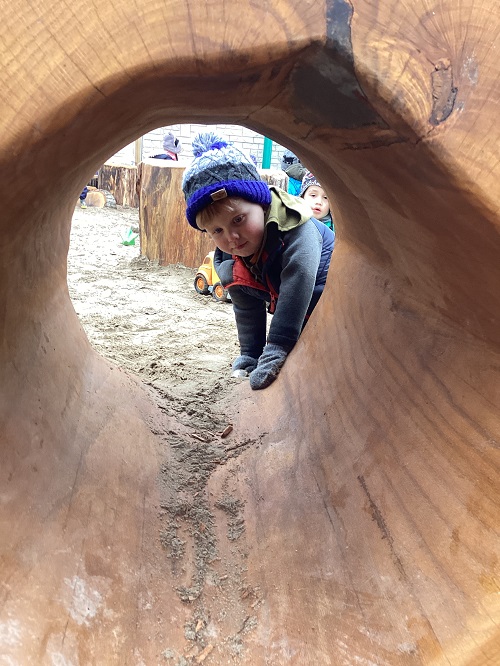 A child looking through a hollowed log