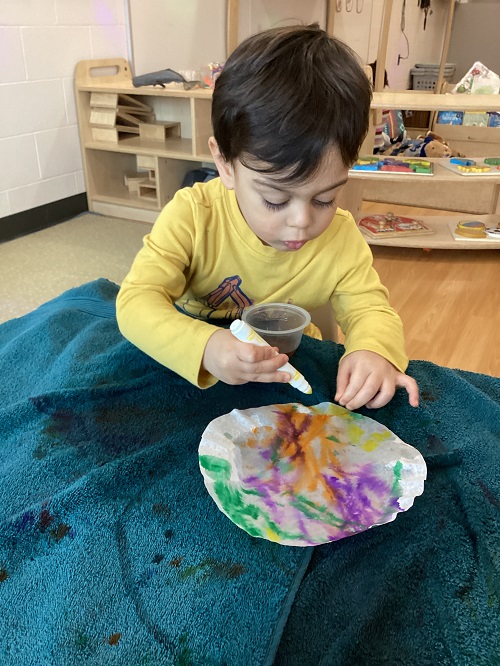 A child using a marker to dye a coffee filter.