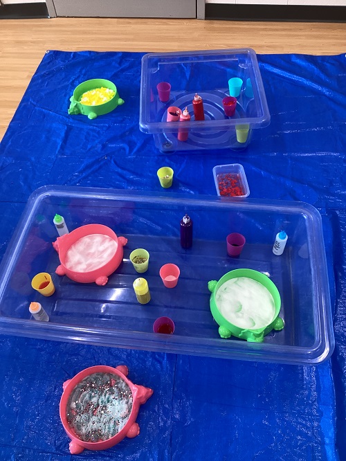 A sensory station filled with bowls of shaving foam and paint