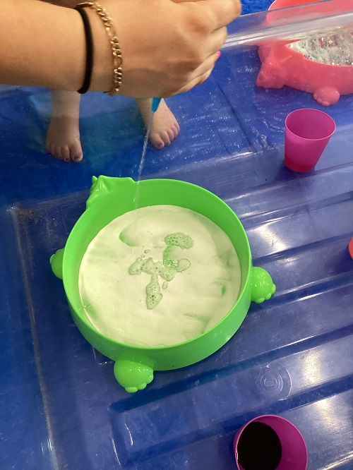 An educator squeezing paint into shaving foam