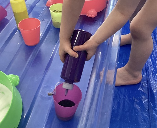 A child squeezing paint into a cup