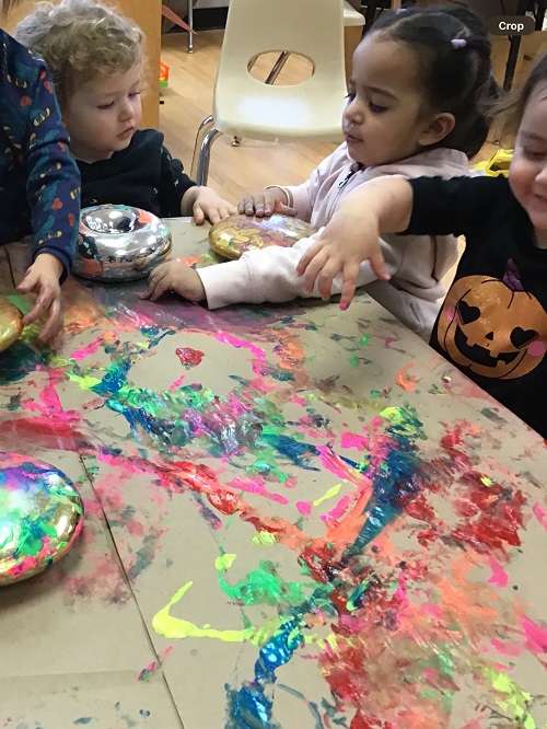 3 Toddler sitting at the table with paint with fingers and mirrored donuts