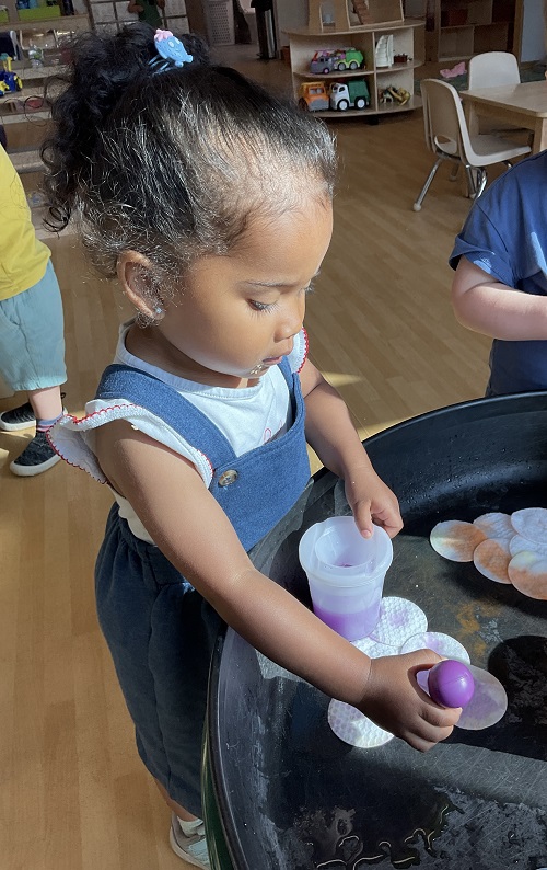 child in blue dress using a dropper