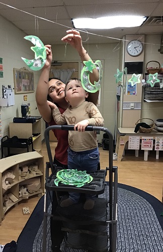 A child and educator putting up decorations in the classroom for Ramadan