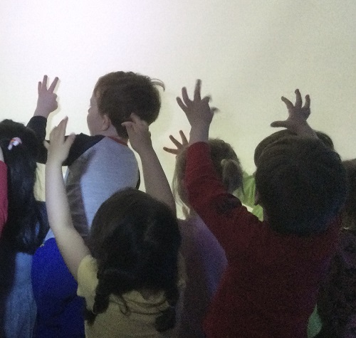 Children making hand shadows on a white screen