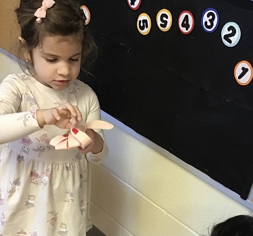 A child folding paper fingers down as she counts