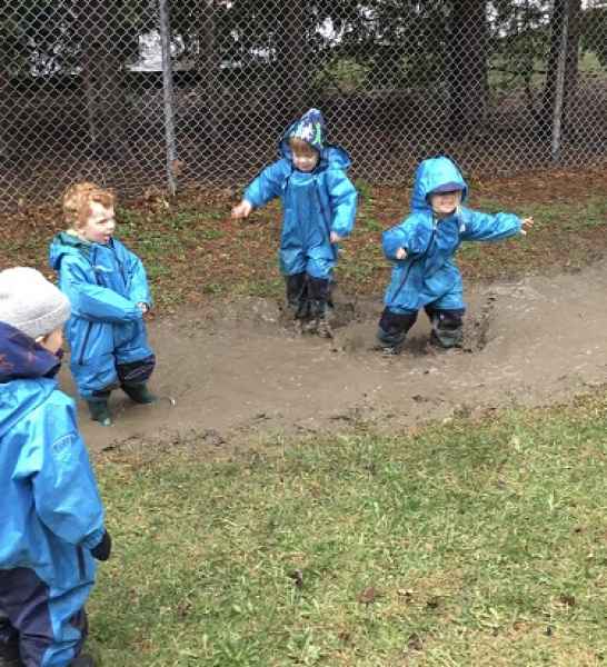 children wearing rain gear splashing in puddles