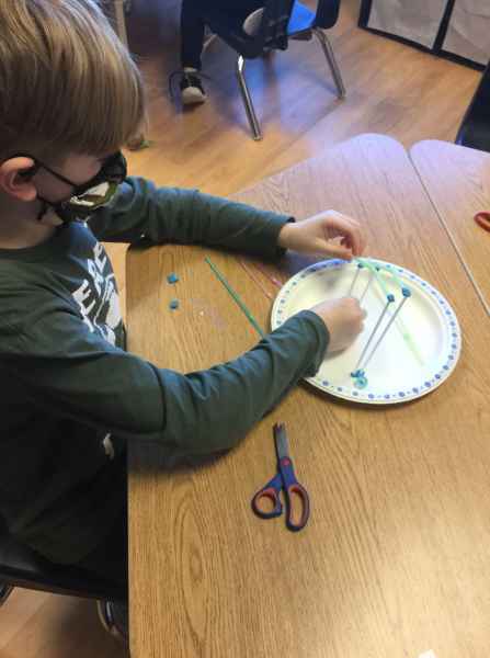 boy building a structure with straws and putty
