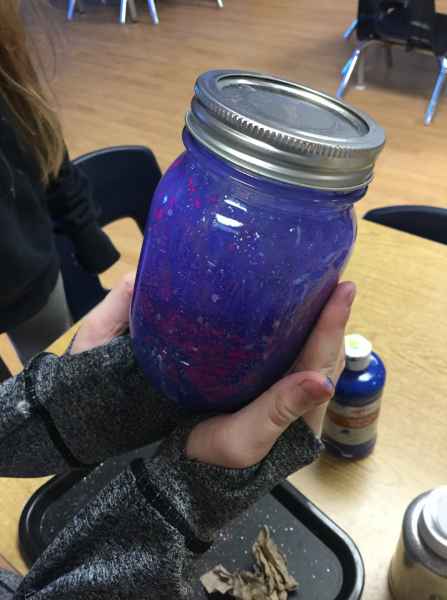 girl holding a glass jar filled with coloured water