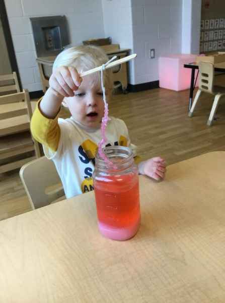 boy holding a popsicle stick with a thread attached