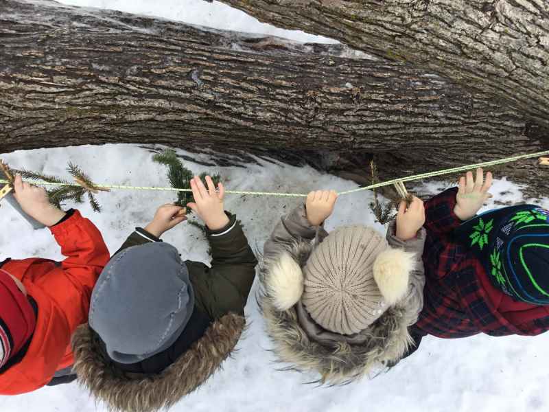children hanging clothpins on a rope outdoors
