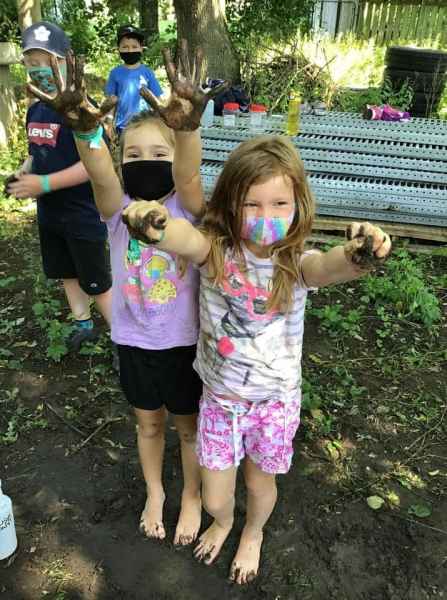 school-age children showing their muddy hands