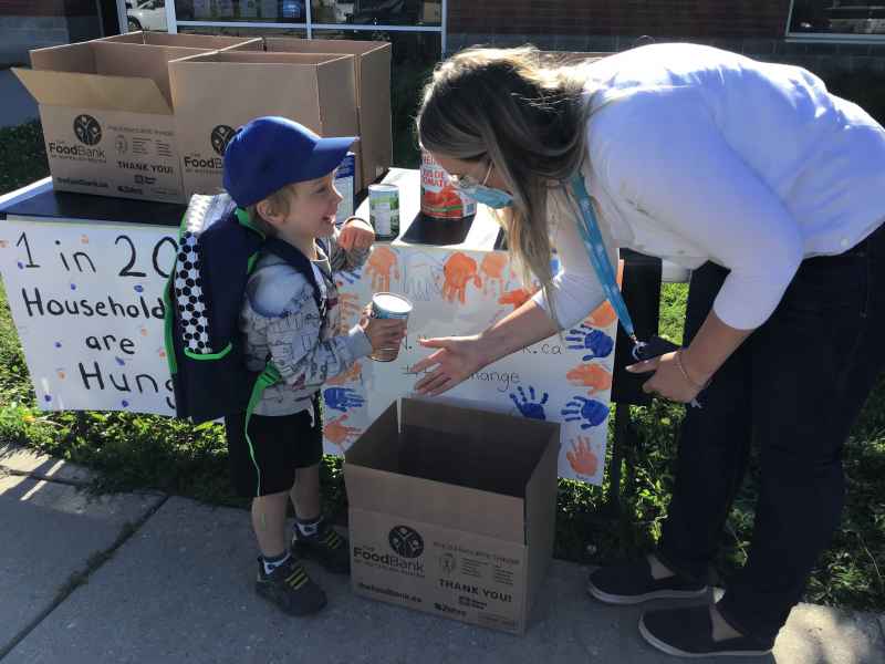 boy putting his donated canned goods into a box of food