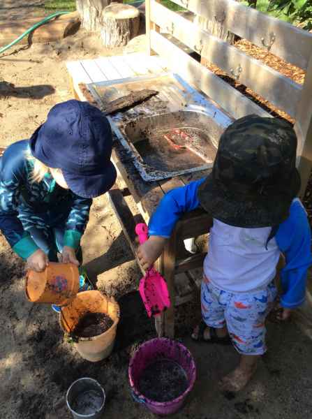 children playing in a mud kitchen outside