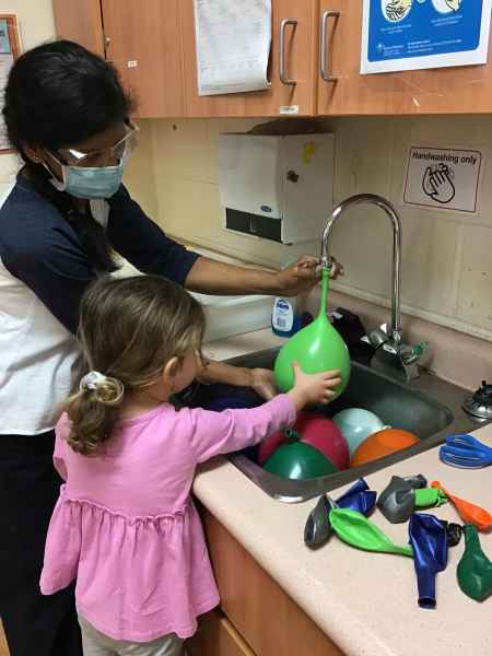 girl and educator filling water balloons in a sink