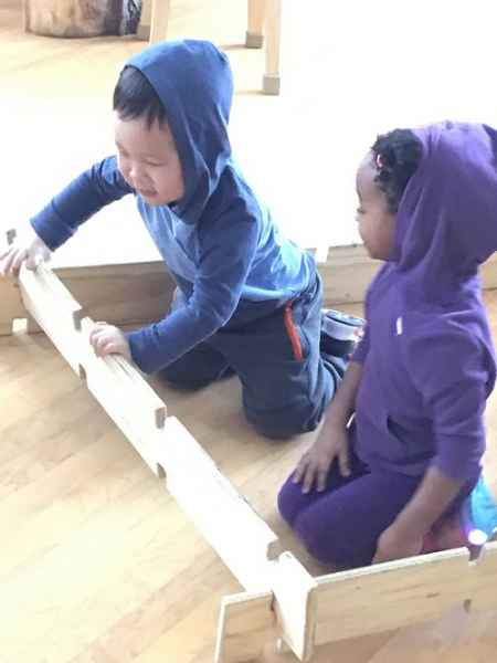 two children building a structure with wood