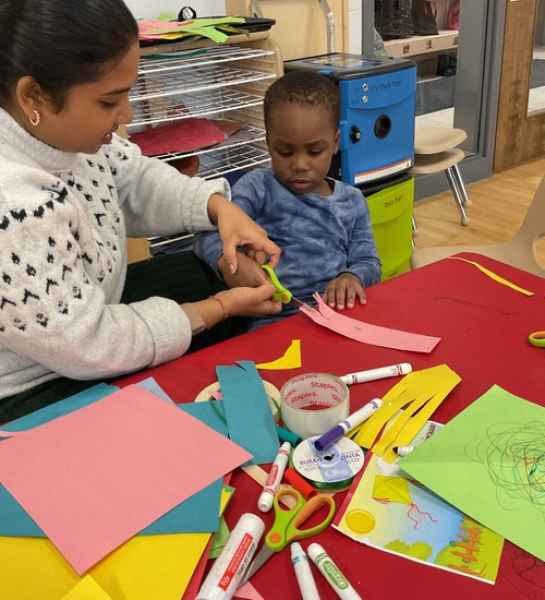 child being assisted in a craft at risingoaks st.patrick