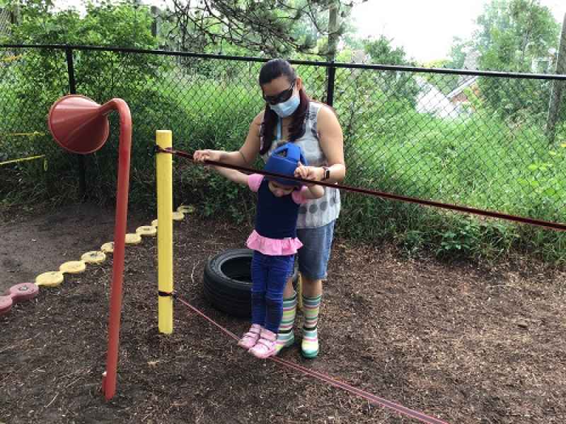 educator helping child balance on a rope tied between two poles